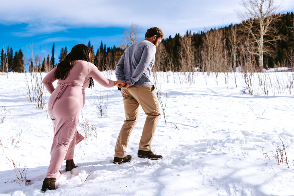 Dad to be helping mama to be through the snowy mountains of colorado for maternity photos 