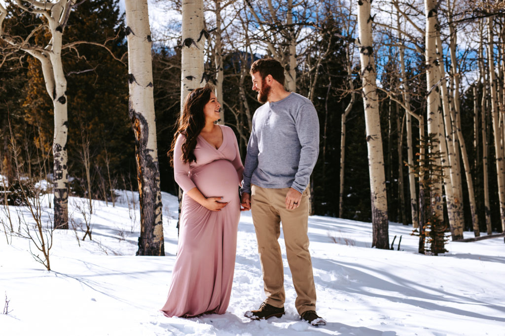 Parents to be looking at each other in a loving way at their mountain maternity session in Colorado 