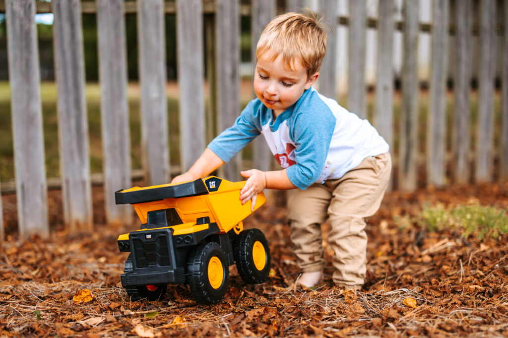 Two Year old boy playing with a cat tractor, at home family photos session in High Points, North Carolina 