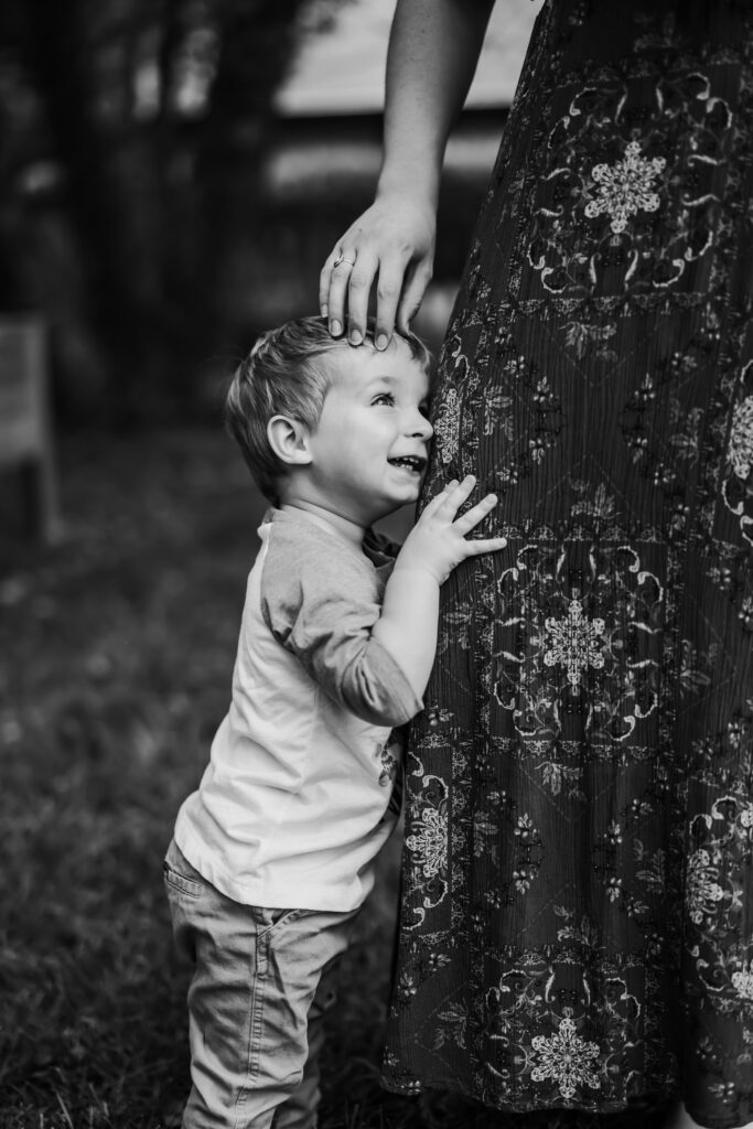 Black and white photo of Son hugging mamas leg, at home family photos session in High Points, North Carolina 