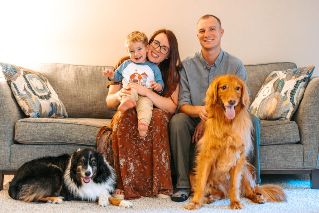 Family posing on couch with their dogs, for their home family photos session in High Points, North Carolina 