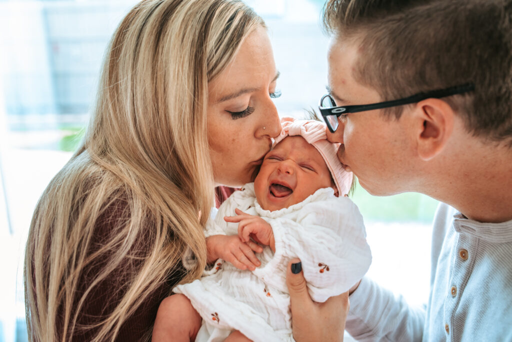 Mom and dad loving on their baby girl, for their in home newborn session