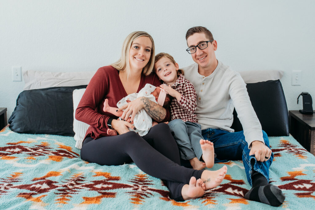 Family of four cuddling their newest baby girl at their in home newborn session 