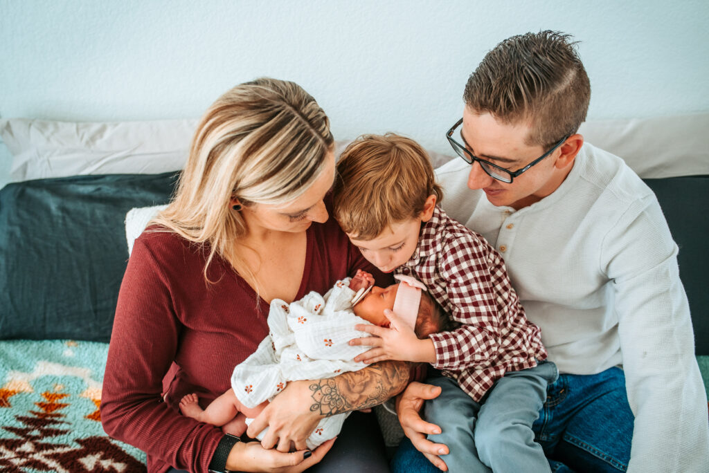 Family of four cuddling their newest baby girl at their in home newborn session 