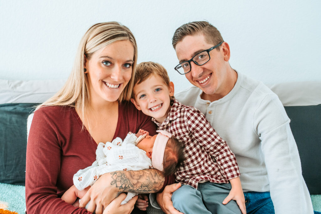 Family of four cuddling their newest baby girl at their in home newborn session 