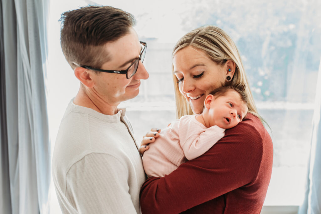 Mom and dad cuddling their baby girl at their in home newborn session 