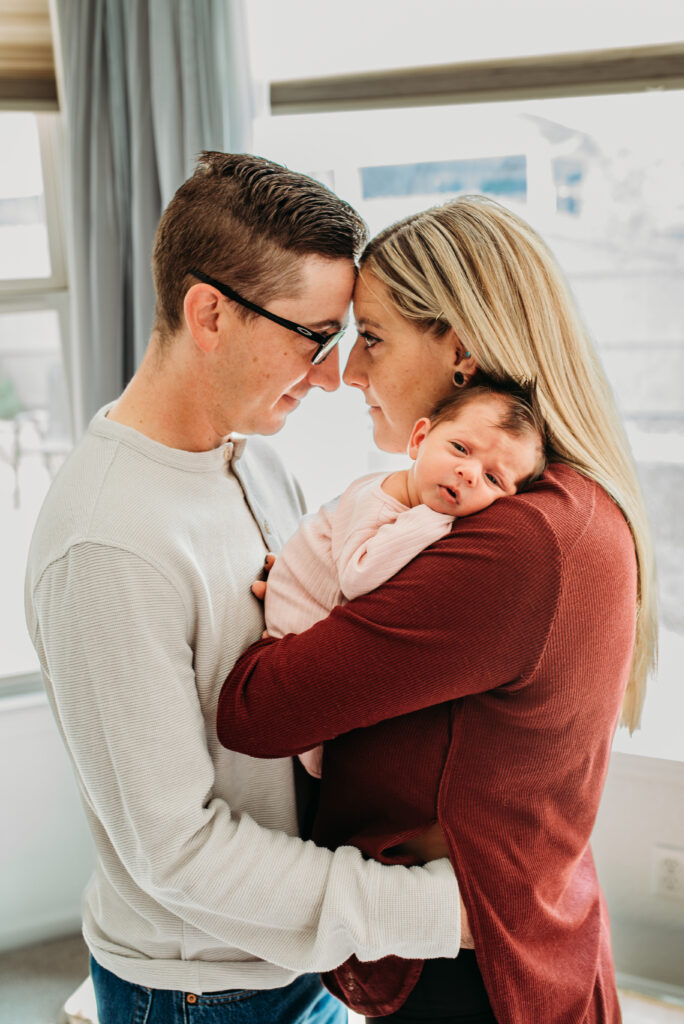 Mom and dad cuddling their baby girl at their in home newborn session 