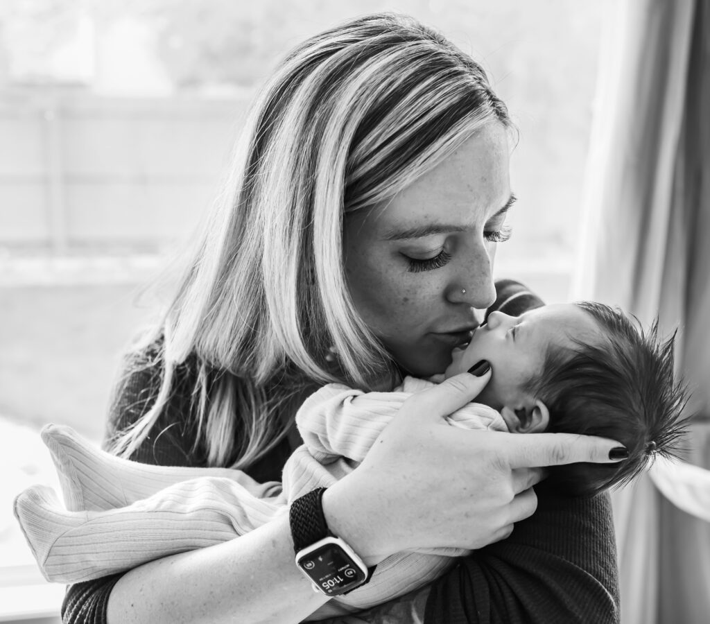 Mom kisses with baby girl at comfy in home newborn session 