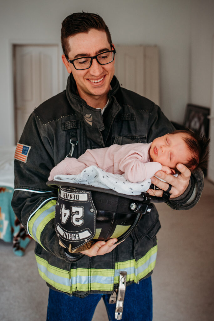 Dad in a fire uniform with his newborn baby girl at their home 