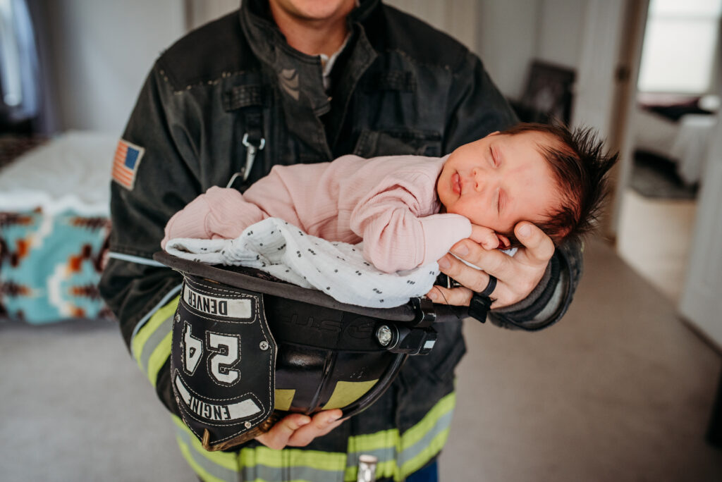 Baby girl in a fire helmet for their in home newborn session 