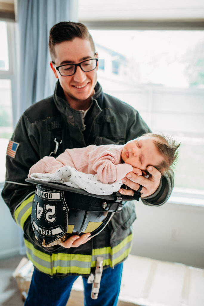 Dad in a fire uniform with his newborn baby girl at their home 