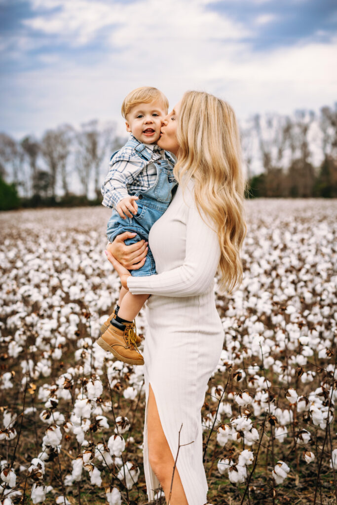 Mother kissing sons cheek in a field of cotton in Albemarle North Carolina 