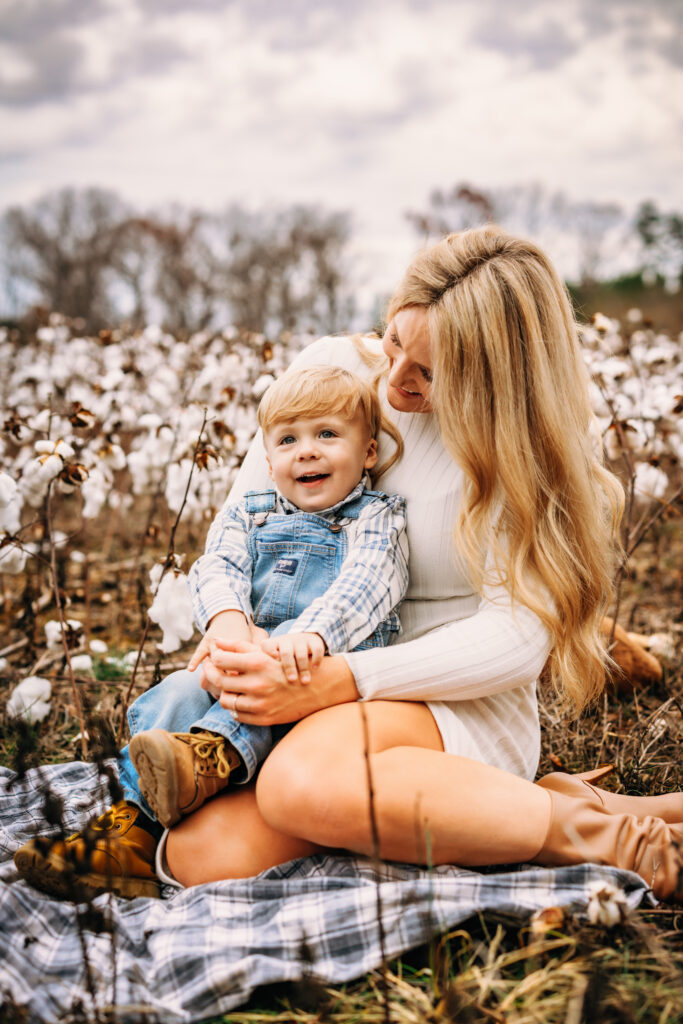 Mother and son sitting on a blanket surrounded by a field of cotton in North Carolina 