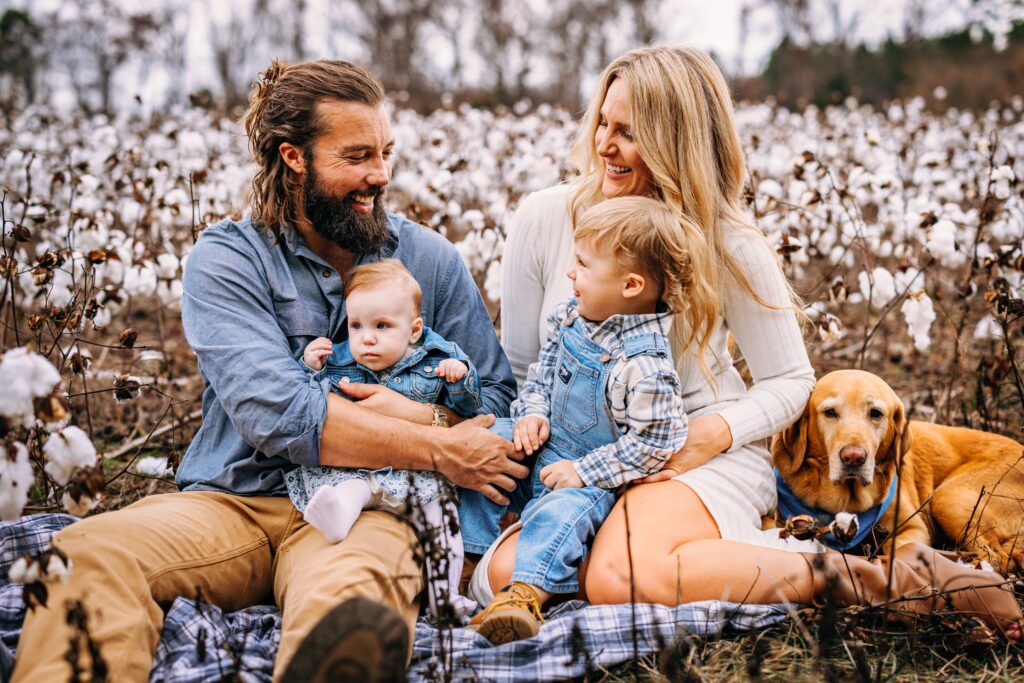 Family sitting on a blanket having a tickle fight in a field of cotton at Family Session in North Carolina 