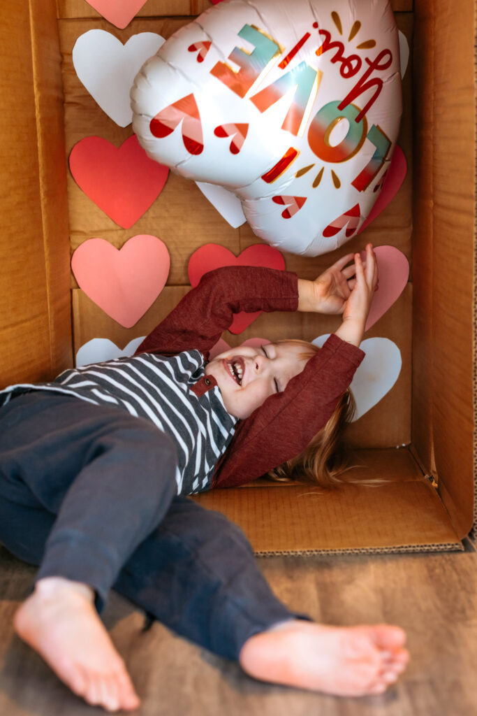 Toddler boy being wild while getting in the cardboard box photos taken 