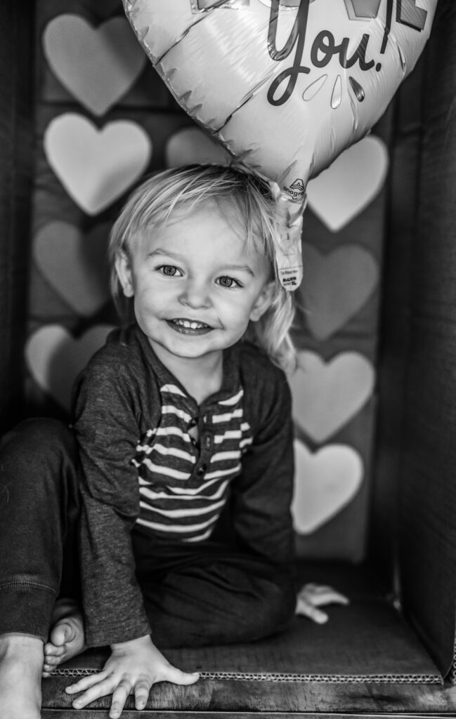 Toddler boy in a cardboard box themed for Valentines Day Photos with RattTrap Artistry 